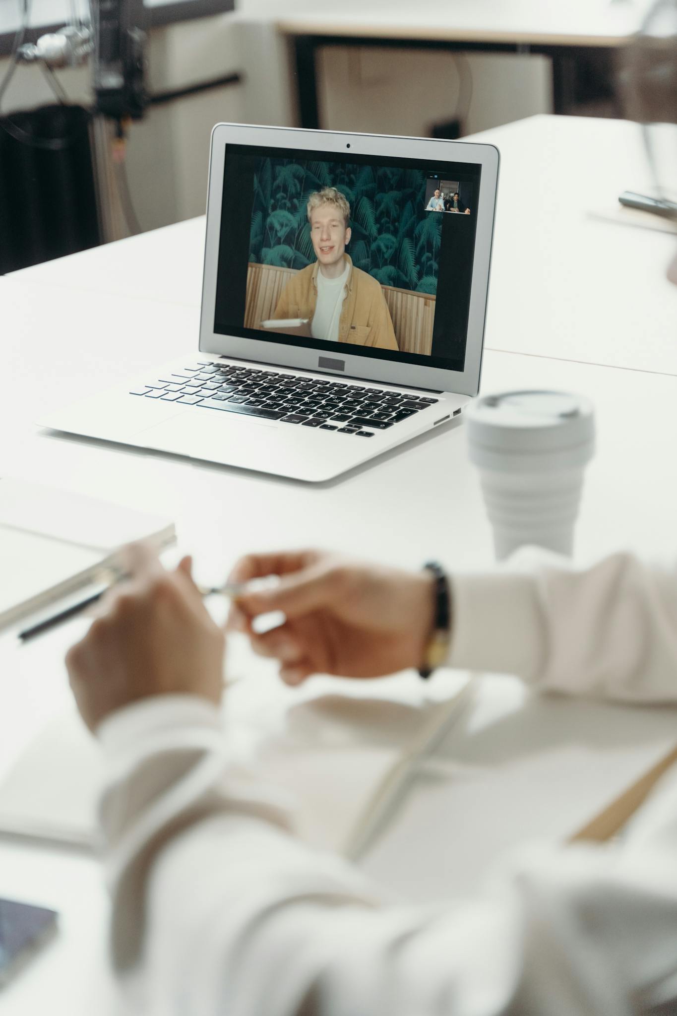 Professional virtual meeting with focus on laptop screen showing a video call participant.